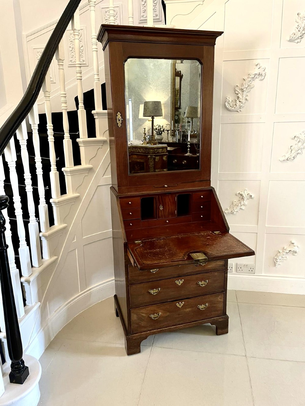 An antique George II mahogany bureau bookcase featuring a mirrored door upper cabinet, a slant-front writing slope, four graduated drawers, and bracket feet. View XI