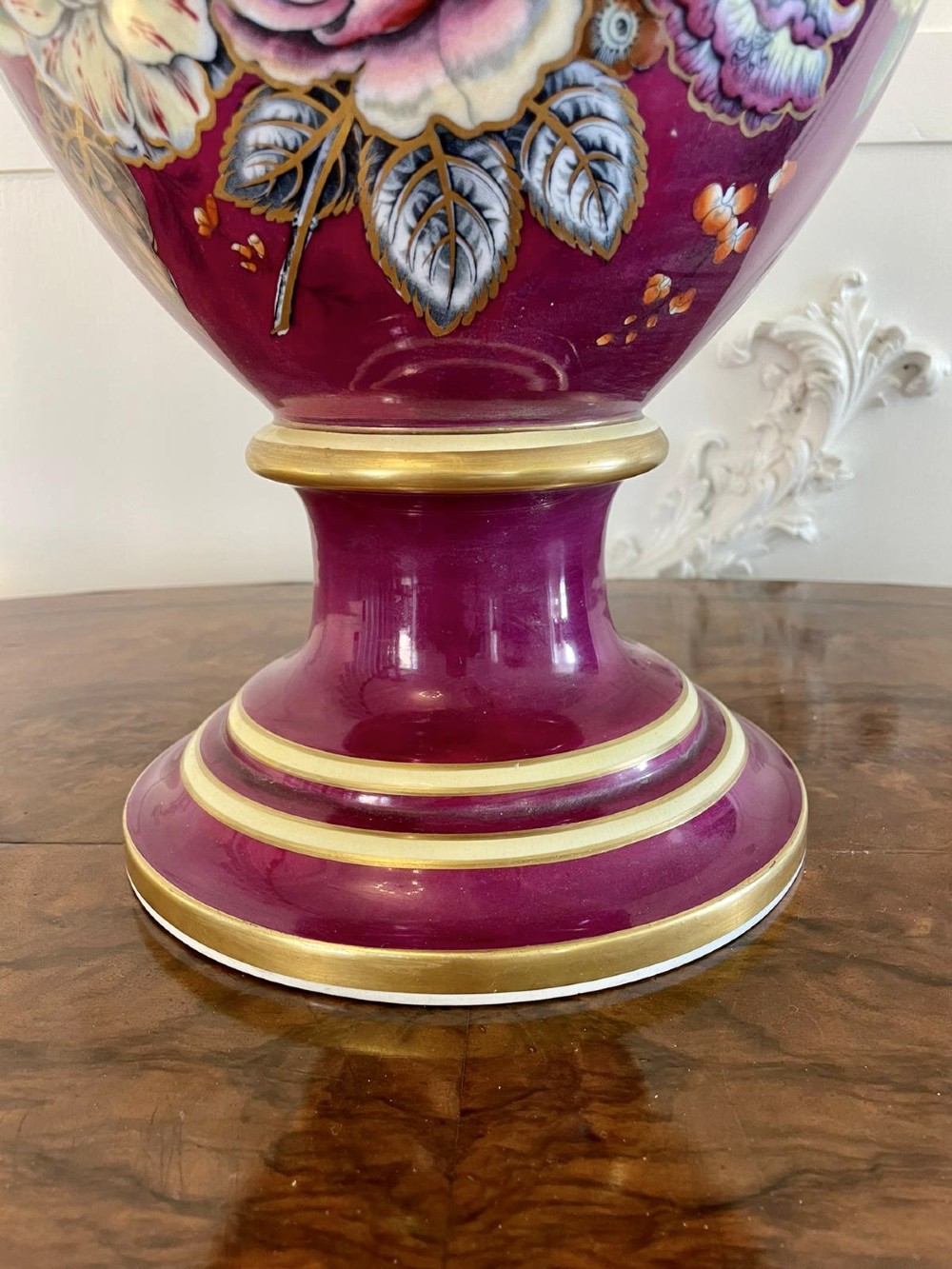 A large Victorian twin-handled porcelain urn vase in vibrant magenta featuring hand-painted botanical florals, navy blue handles, and gold leaf gilding. View III