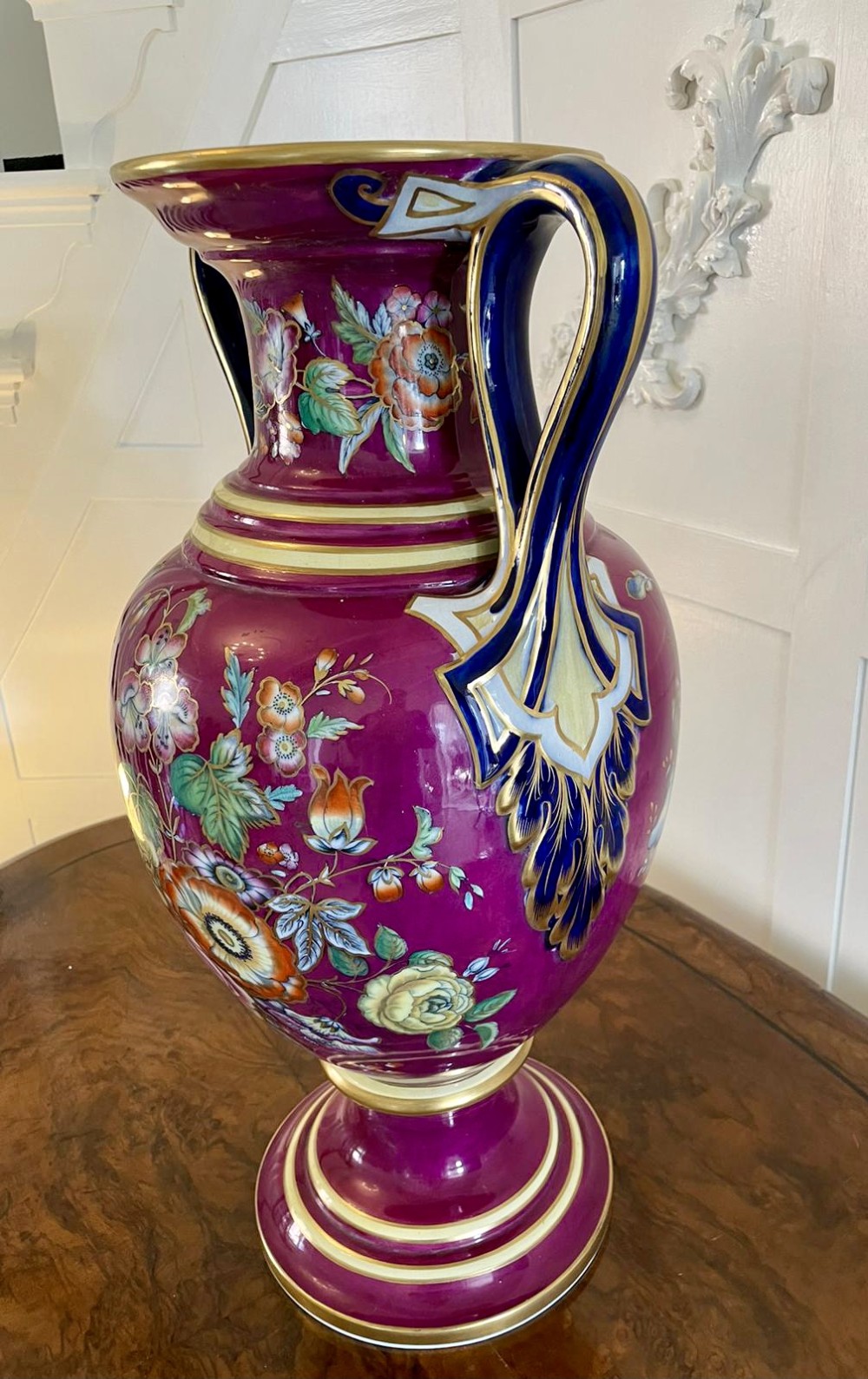 A large Victorian twin-handled porcelain urn vase in vibrant magenta featuring hand-painted botanical florals, navy blue handles, and gold leaf gilding. View VII