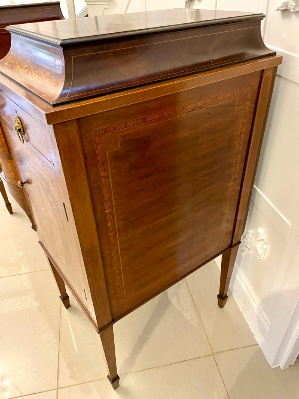 A nineteenth-century mahogany sideboard with detailed floral marquetry inlays, a stepped pedestal top, multiple drawers with brass lion mask ring handles, and tapered square legs. View V