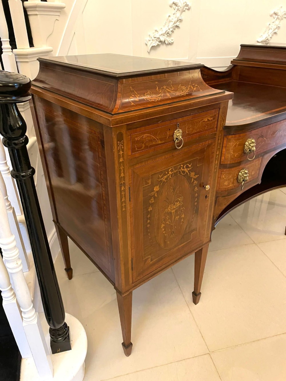A nineteenth-century mahogany sideboard with detailed floral marquetry inlays, a stepped pedestal top, multiple drawers with brass lion mask ring handles, and tapered square legs. View VII