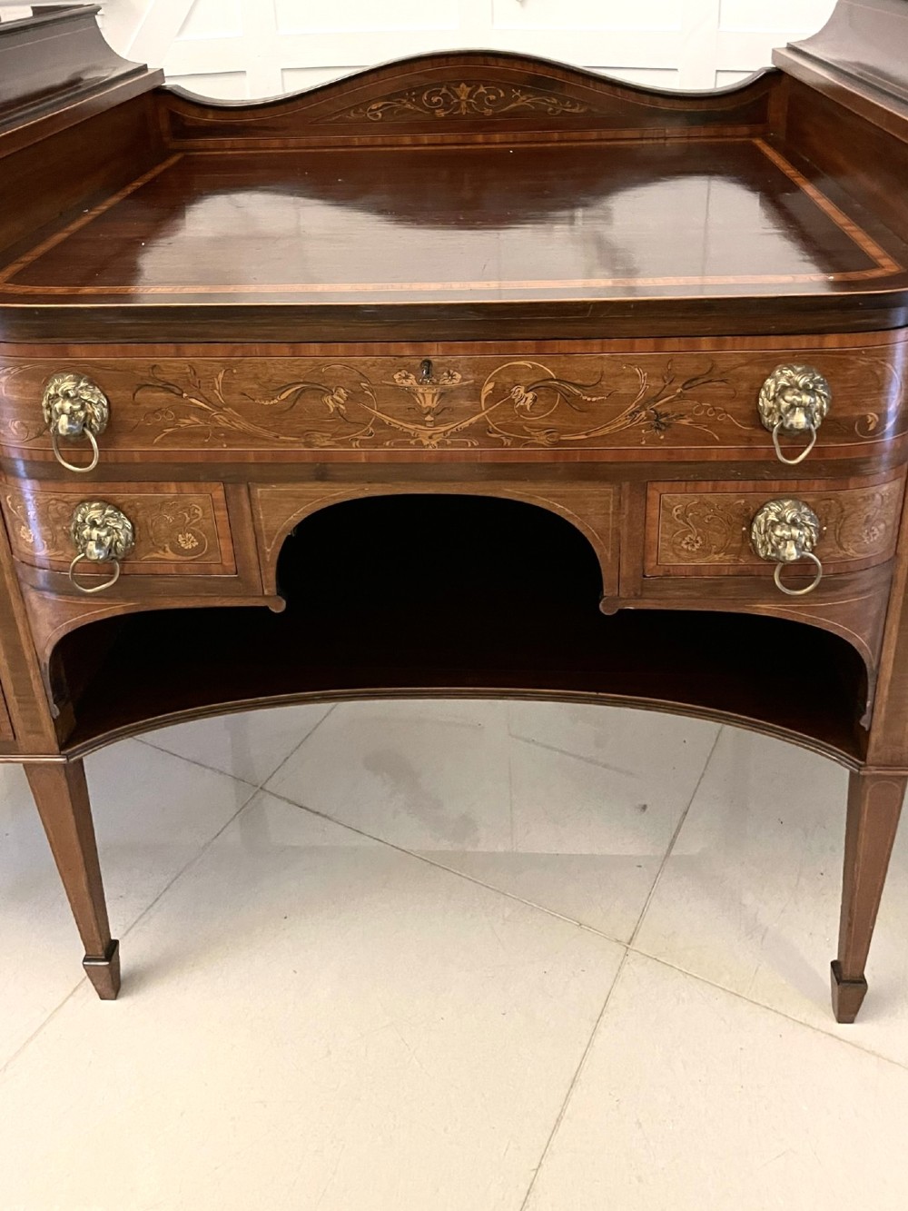 A nineteenth-century mahogany sideboard with detailed floral marquetry inlays, a stepped pedestal top, multiple drawers with brass lion mask ring handles, and tapered square legs. View IX