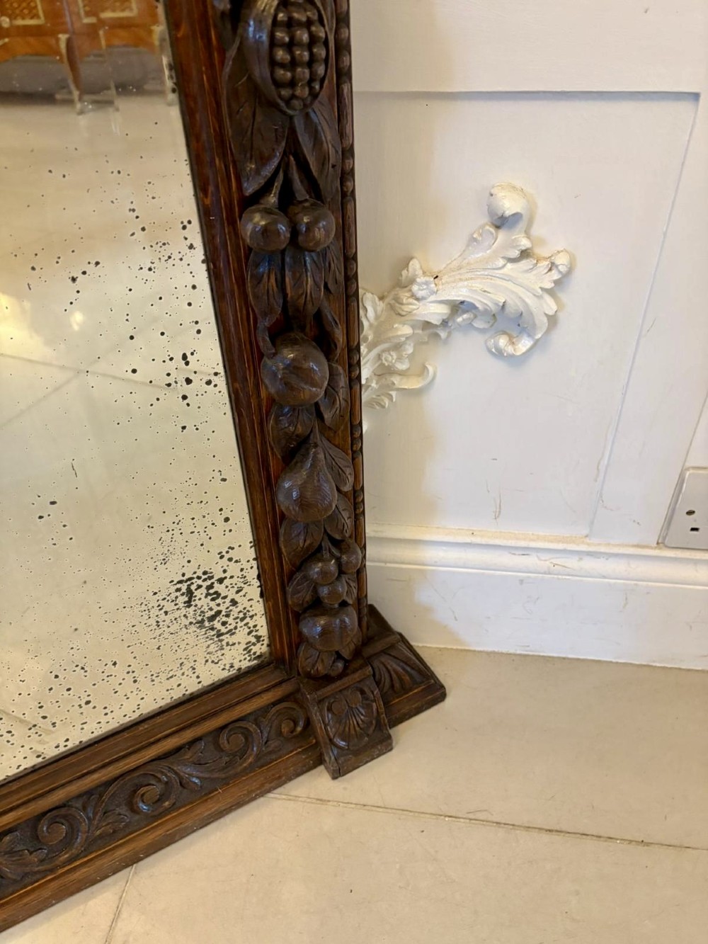 A 19th-century Victorian dark oak wall mirror featuring carved fruit and leaf motifs along the frame and a curved cresting pediment. View II