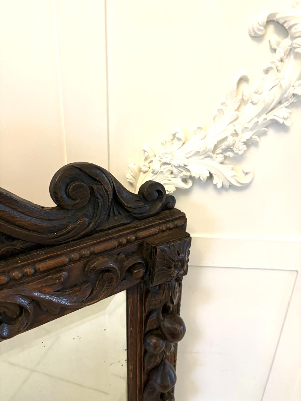 A 19th-century Victorian dark oak wall mirror featuring carved fruit and leaf motifs along the frame and a curved cresting pediment. View IV