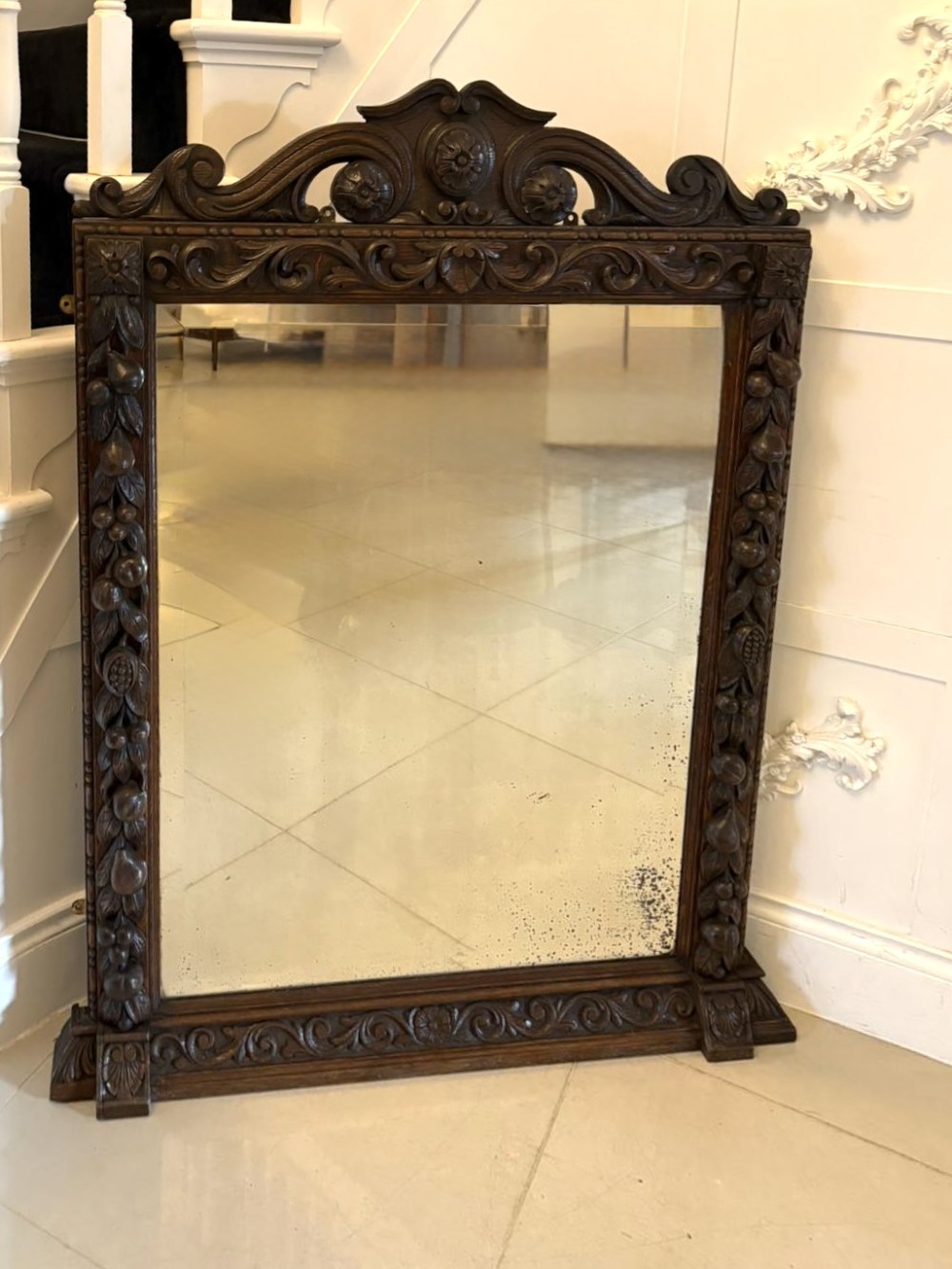 A 19th-century Victorian dark oak wall mirror featuring carved fruit and leaf motifs along the frame and a curved cresting pediment.