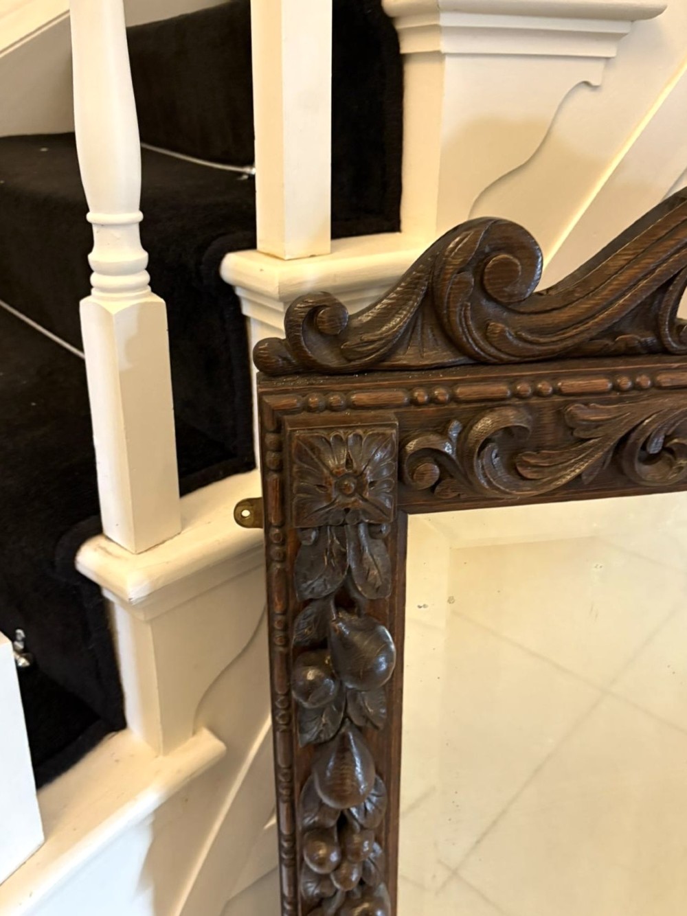 A 19th-century Victorian dark oak wall mirror featuring carved fruit and leaf motifs along the frame and a curved cresting pediment. View VI