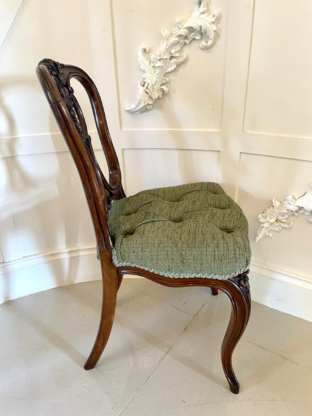 A set of four Victorian French carved walnut side chairs featuring openwork backrests and button-upholstered sage green fabric seats on cabriole legs. View VI