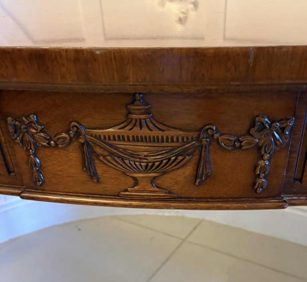 A pair of polished mahogany serpentine-front console tables featuring fluted aprons, carved central urn motifs, and tapered fluted legs. View XIII