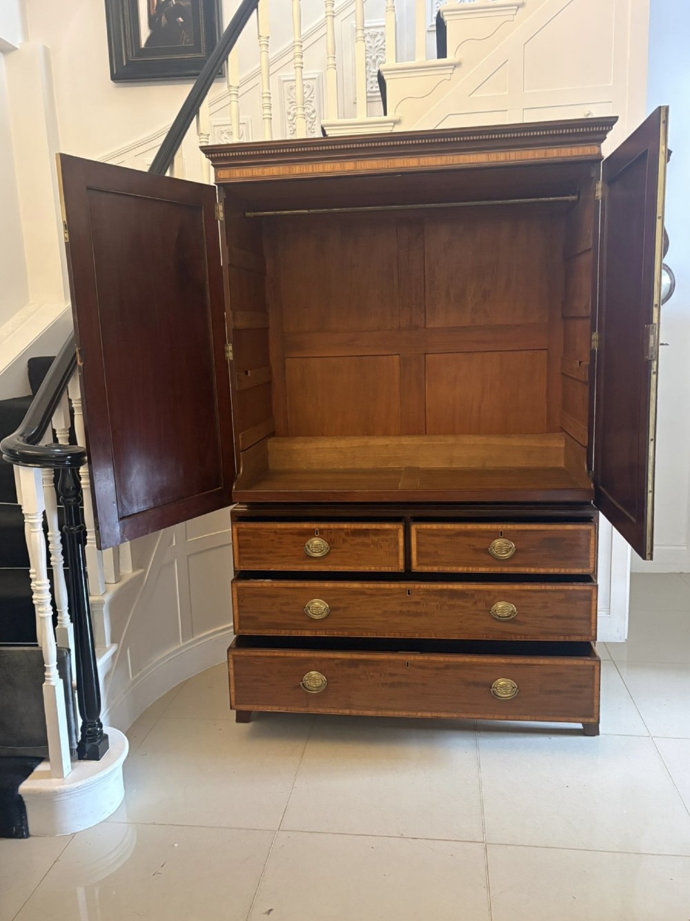 An antique Georgian mahogany linen press featuring two doors decorated with oval satinwood urn marquetry inlays situated above four drawers with brass handles. View XII