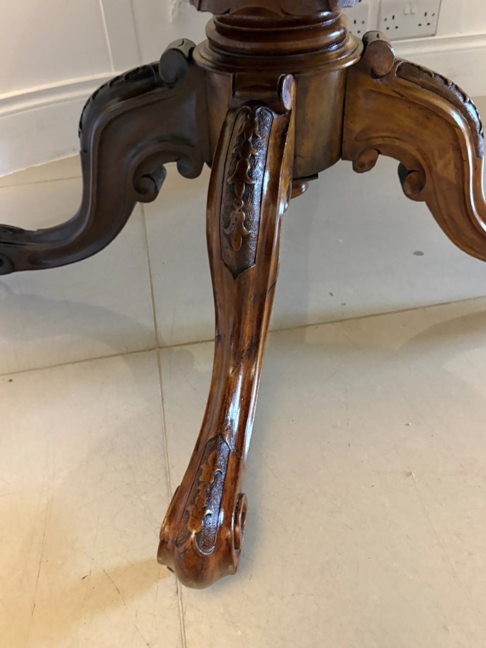 An antique Victorian oval tilt-top dining table featuring book-matched burr walnut grain mounted on a carved central column and tripod base with castors. View IX