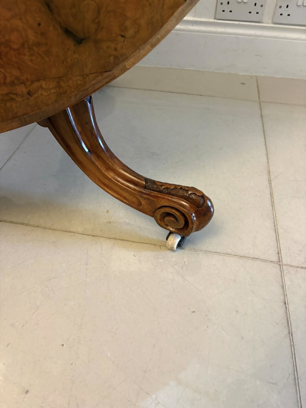 An antique Victorian oval tilt-top dining table featuring book-matched burr walnut grain mounted on a carved central column and tripod base with castors. View XIII