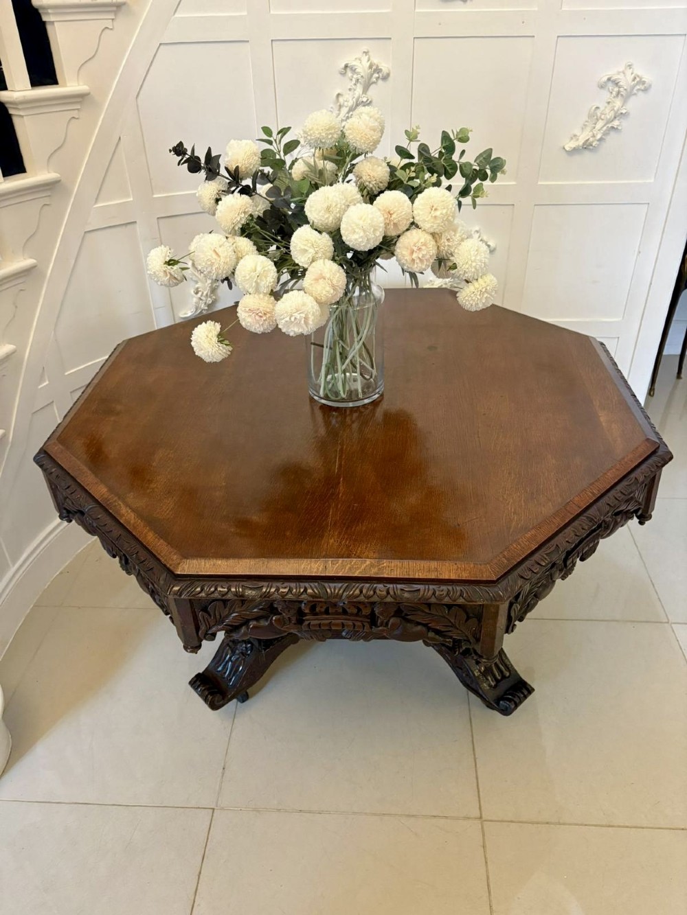 An antique Victorian octagonal dark oak centre table featuring heavily carved foliate designs along the apron and a sturdy central base. View II