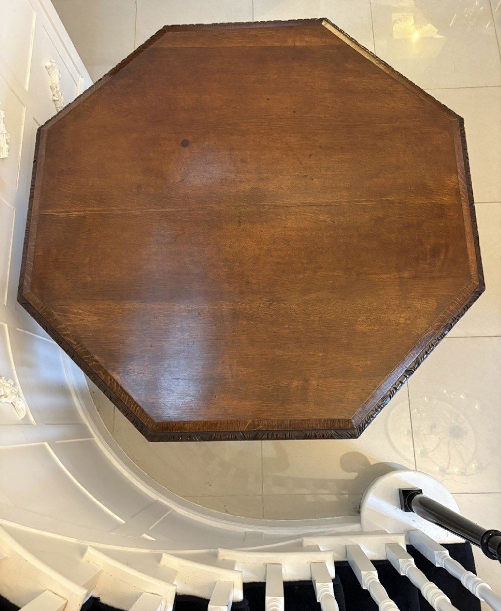 An antique Victorian octagonal dark oak centre table featuring heavily carved foliate designs along the apron and a sturdy central base. View V