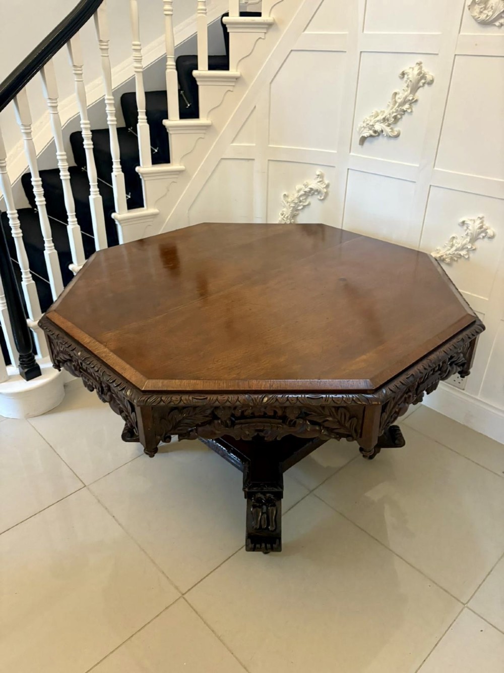 An antique Victorian octagonal dark oak centre table featuring heavily carved foliate designs along the apron and a sturdy central base.