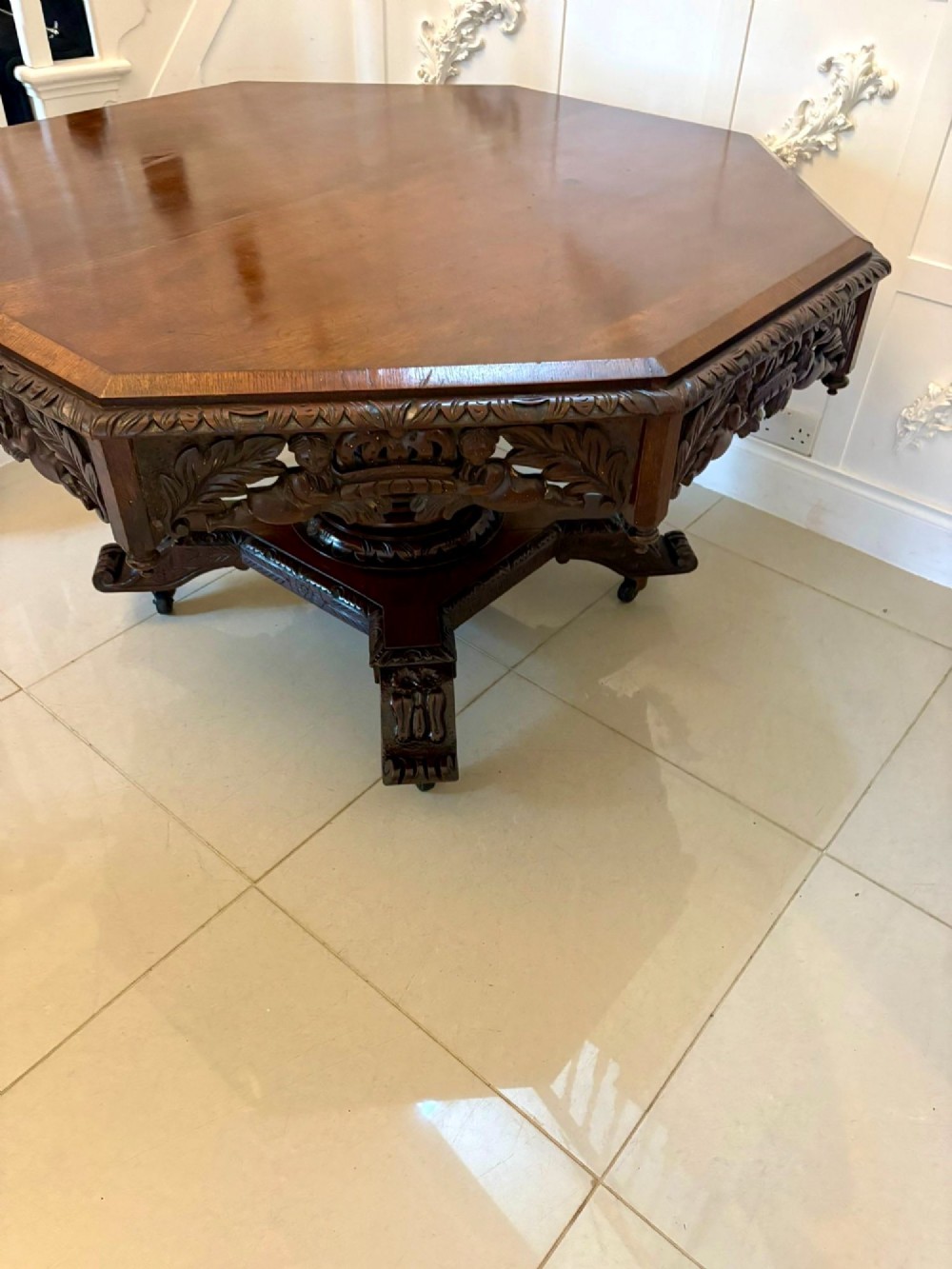 An antique Victorian octagonal dark oak centre table featuring heavily carved foliate designs along the apron and a sturdy central base. View IX