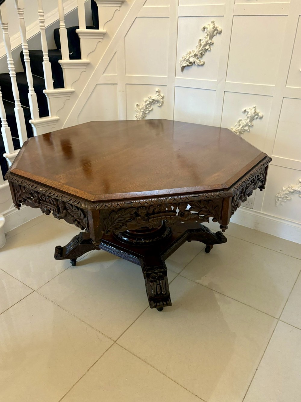 An antique Victorian octagonal dark oak centre table featuring heavily carved foliate designs along the apron and a sturdy central base. View XII