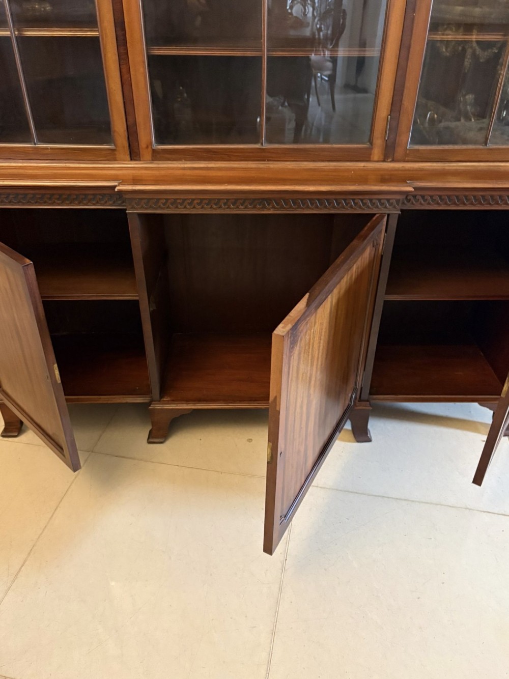 An antique Edwardian mahogany breakfront bookcase featuring three glazed upper doors with astragal moulding above three solid wooden cabinet doors. View IV