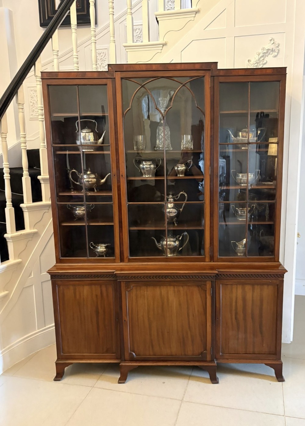 An antique Edwardian mahogany breakfront bookcase featuring three glazed upper doors with astragal moulding above three solid wooden cabinet doors. View V