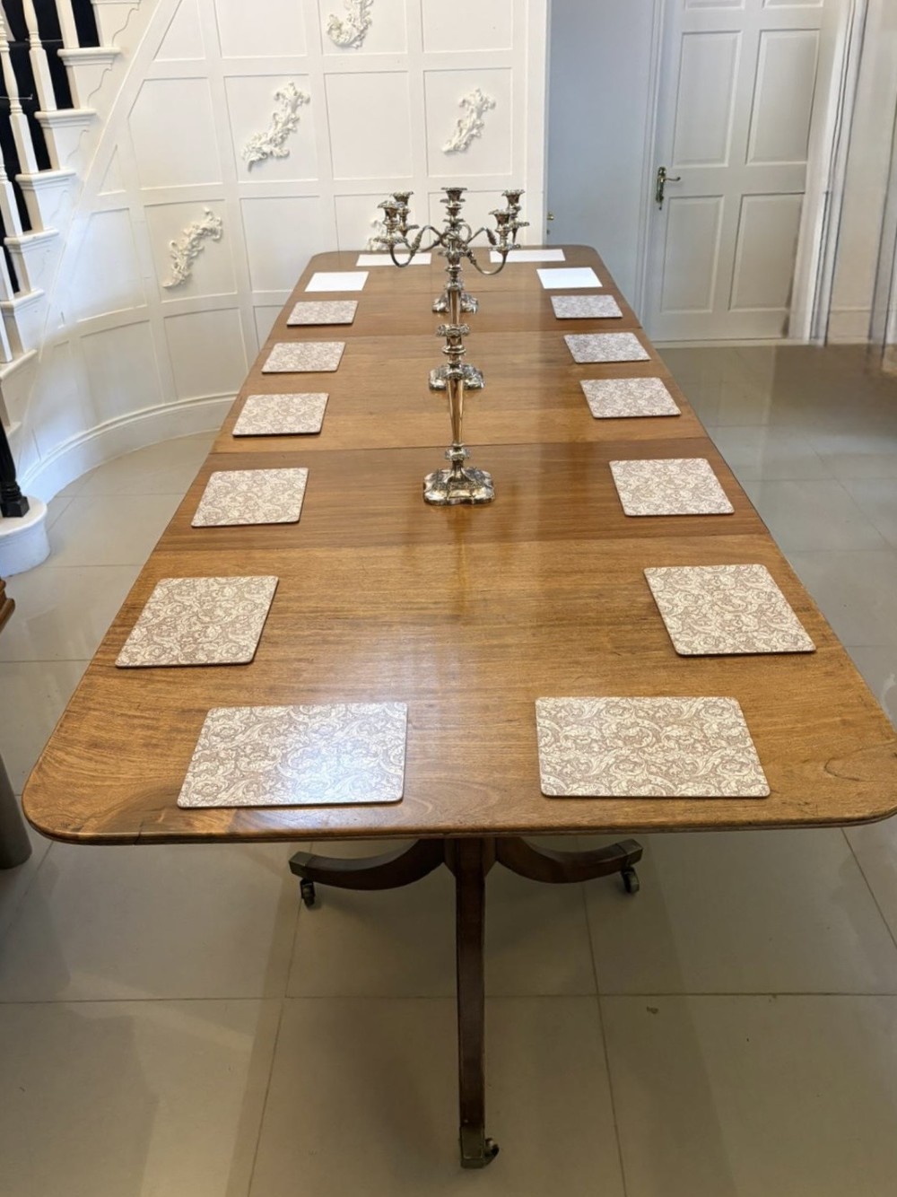 A long Regency mahogany extending dining table supported by turned pedestal pillars with splayed legs and brass castors. View VII