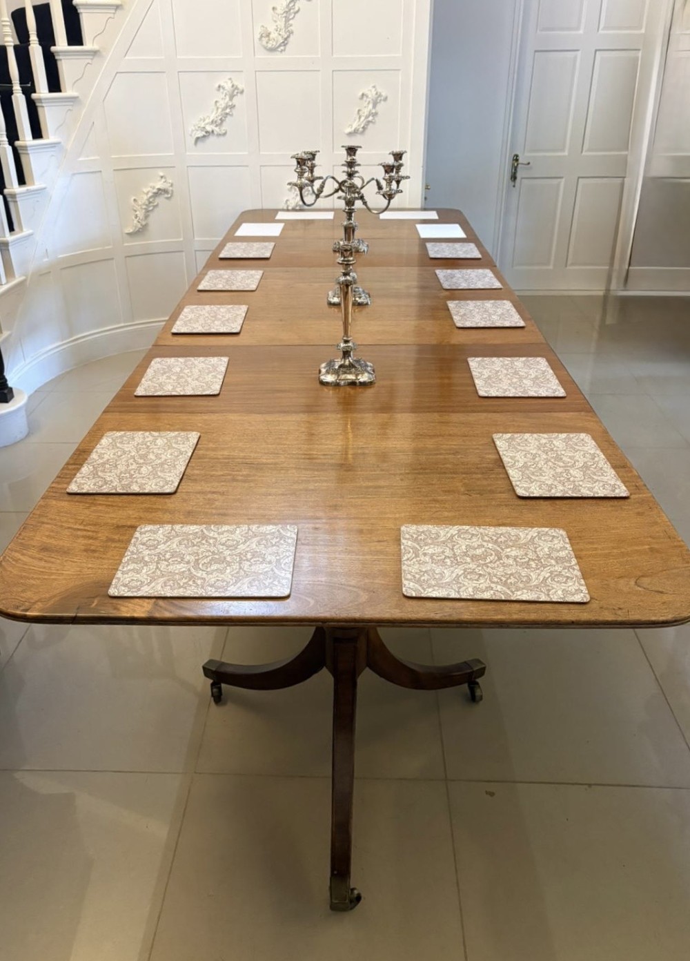 A long Regency mahogany extending dining table supported by turned pedestal pillars with splayed legs and brass castors. View IX