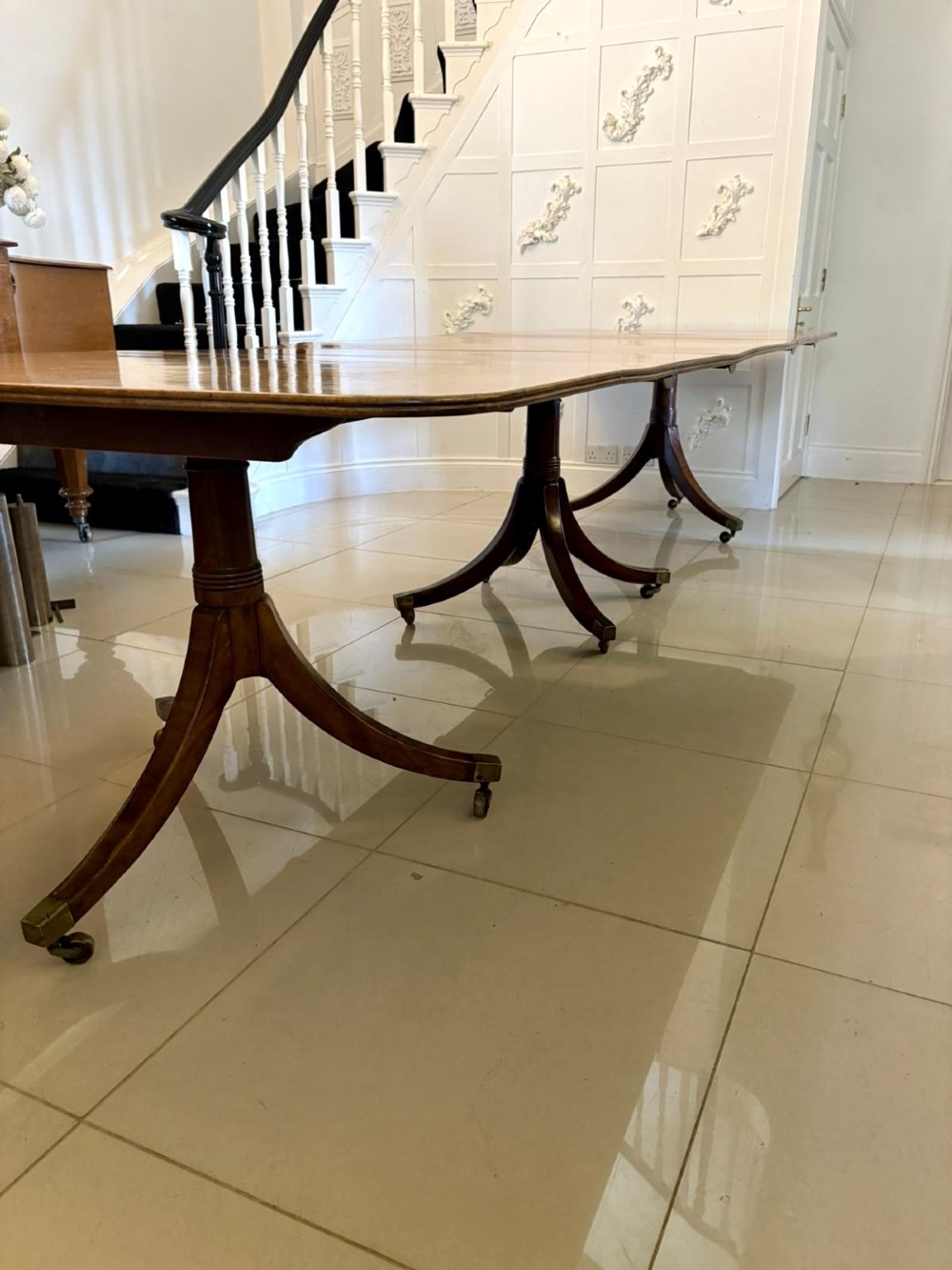 A long Regency mahogany extending dining table supported by turned pedestal pillars with splayed legs and brass castors. View XI