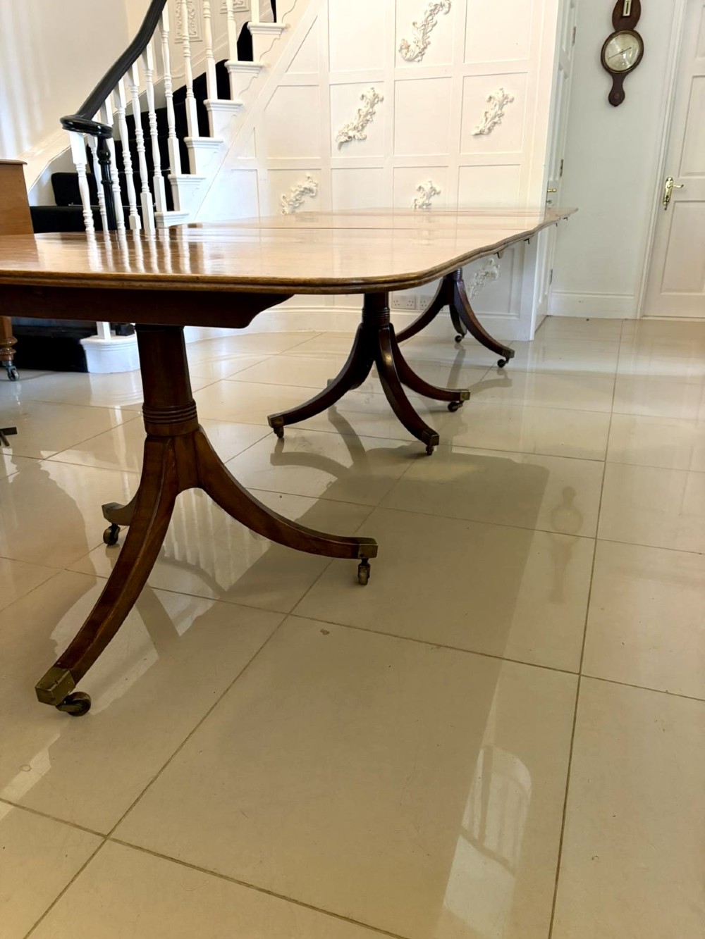 A long Regency mahogany extending dining table supported by turned pedestal pillars with splayed legs and brass castors. View XIII