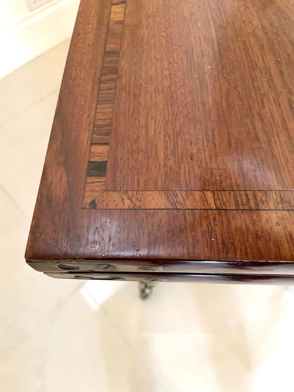 A Regency mahogany fold-over card table featuring an inlaid apron, central pedestal support, and four sabre legs with brass lion paw feet and castors. View V