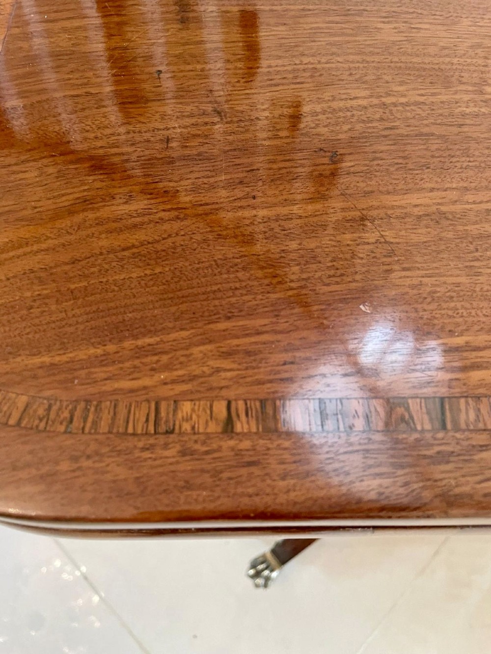A Regency mahogany fold-over card table featuring an inlaid apron, central pedestal support, and four sabre legs with brass lion paw feet and castors. View X