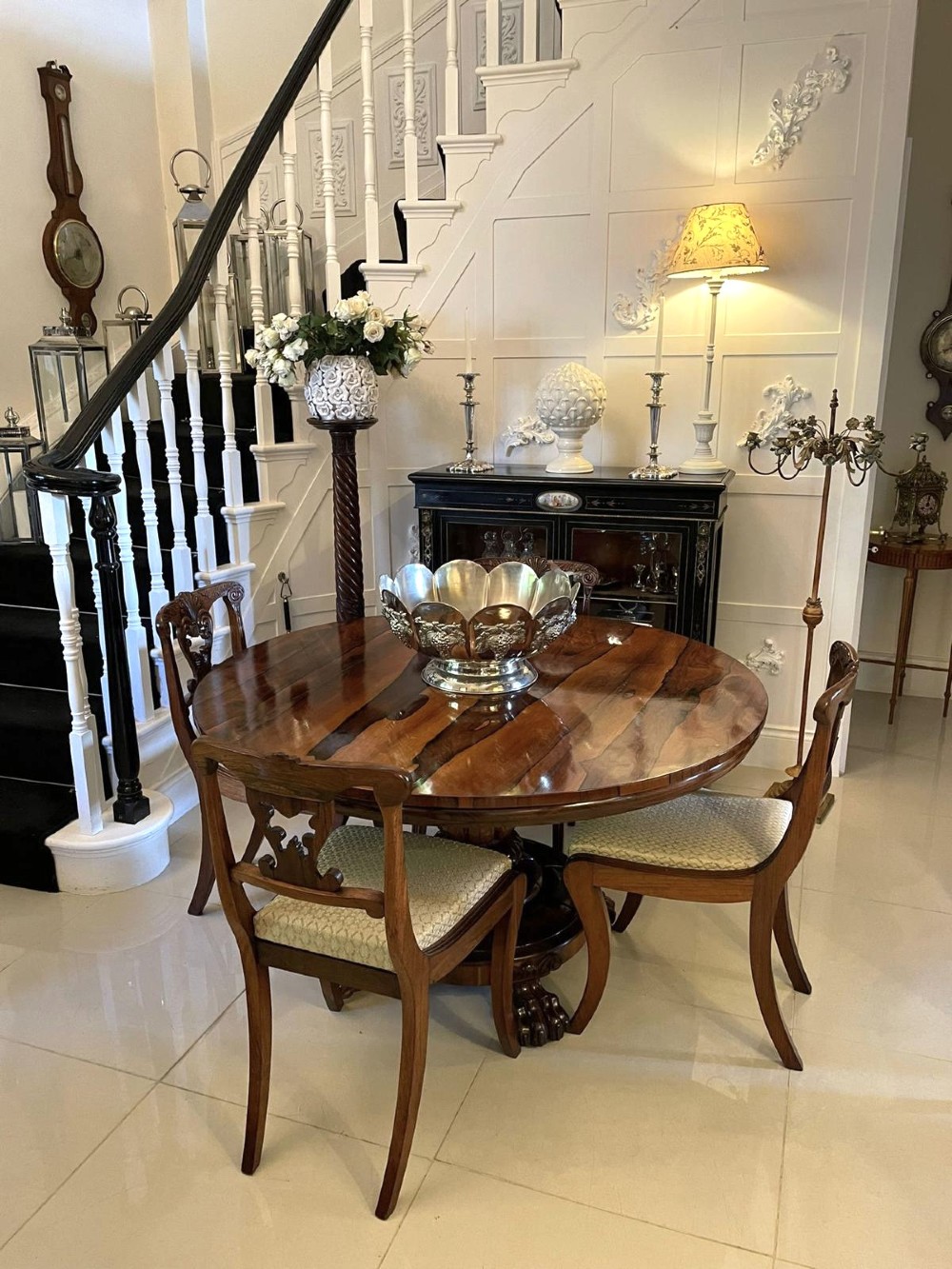 A circular William IV rosewood dining table shown with its top tilted vertically to display the rich wood grain and supported on a carved base with paw feet. View II