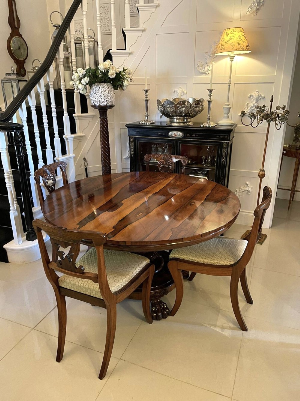 A circular William IV rosewood dining table shown with its top tilted vertically to display the rich wood grain and supported on a carved base with paw feet. View VIII