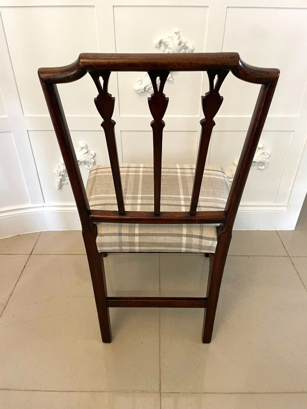 A set of eight George III mahogany dining chairs featuring carved vertical back splats and beige plaid upholstered drop-in seats, including six side chairs and two armchairs. View V