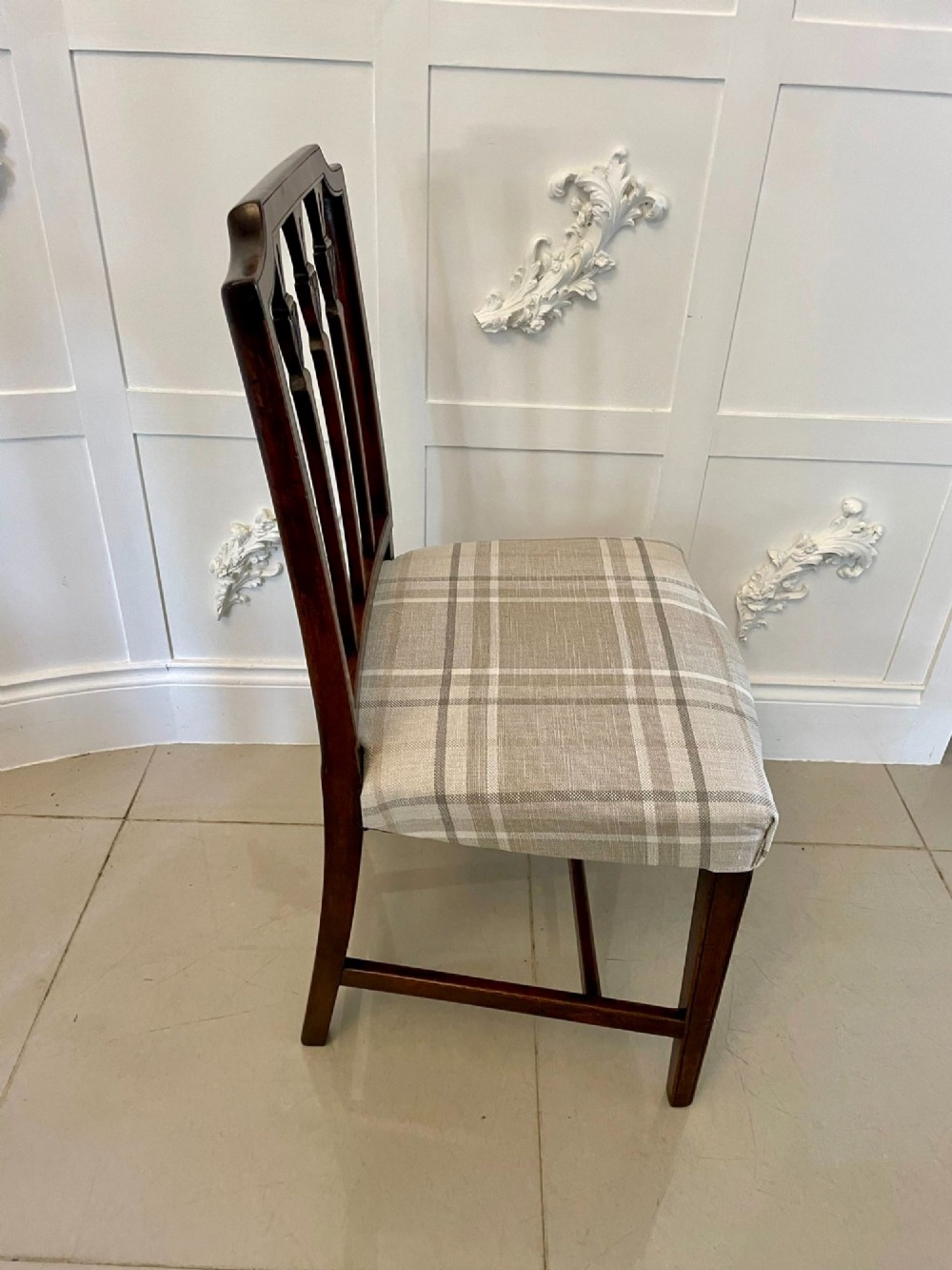 A set of eight George III mahogany dining chairs featuring carved vertical back splats and beige plaid upholstered drop-in seats, including six side chairs and two armchairs. View VI