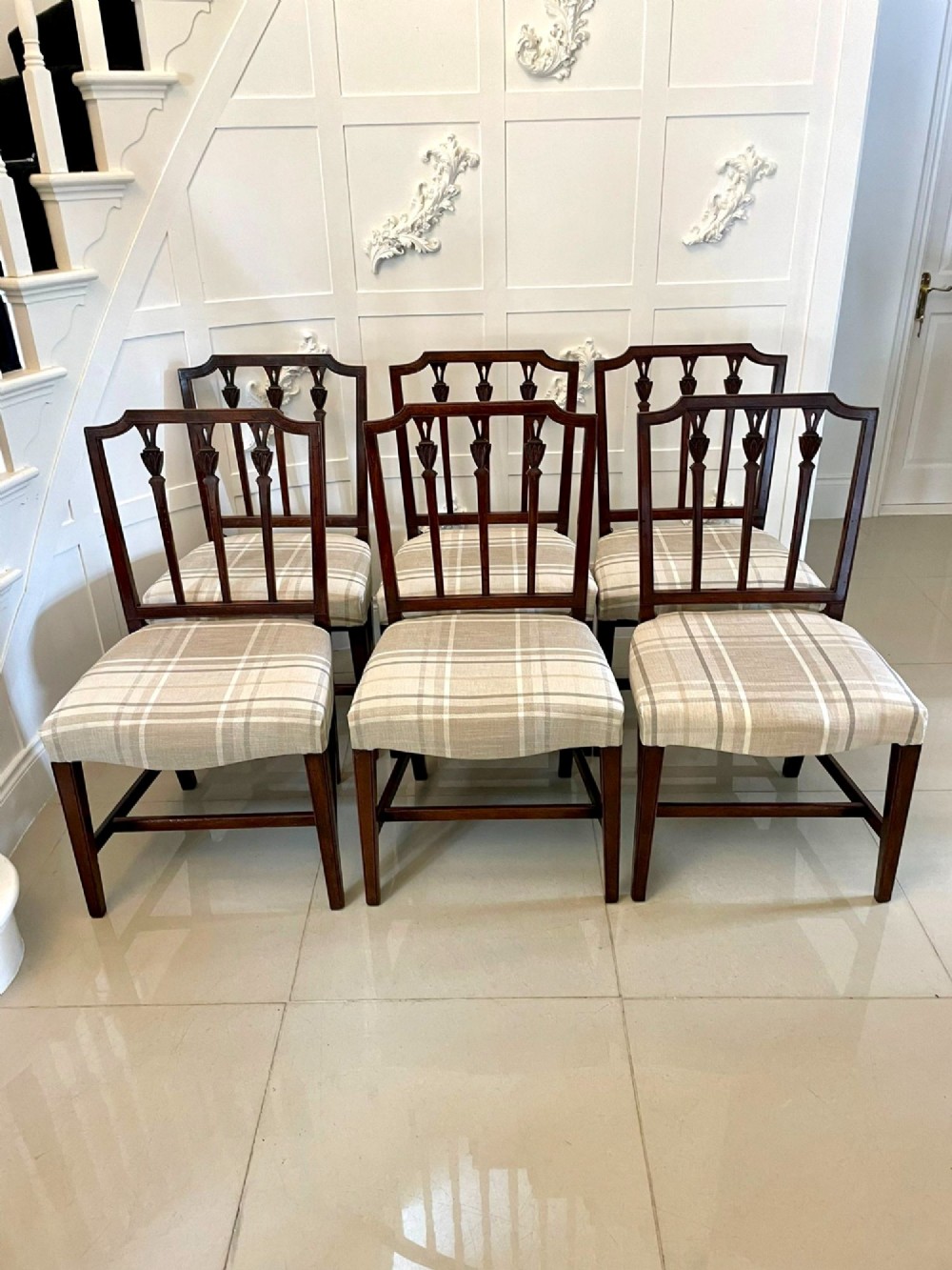 A set of eight George III mahogany dining chairs featuring carved vertical back splats and beige plaid upholstered drop-in seats, including six side chairs and two armchairs. View VIII