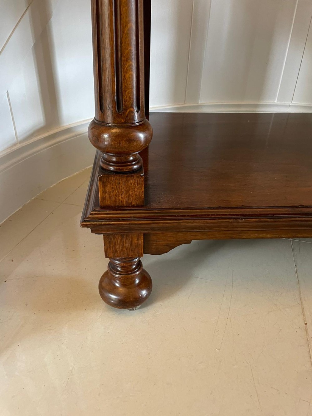 A three-tiered dark oak antique dumbwaiter featuring carved column supports, a carved gallery cresting, and bun feet. View II