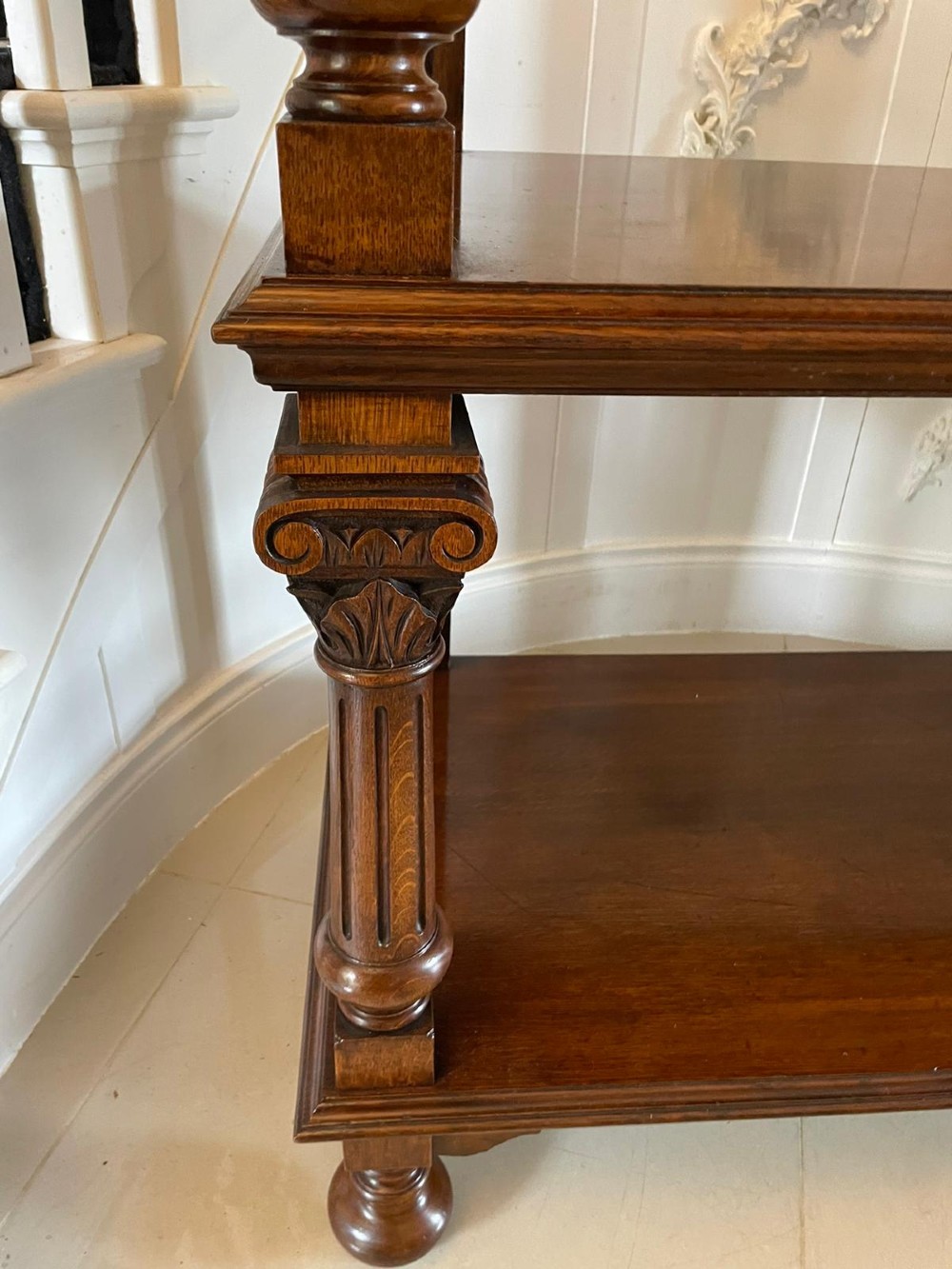 A three-tiered dark oak antique dumbwaiter featuring carved column supports, a carved gallery cresting, and bun feet. View IV