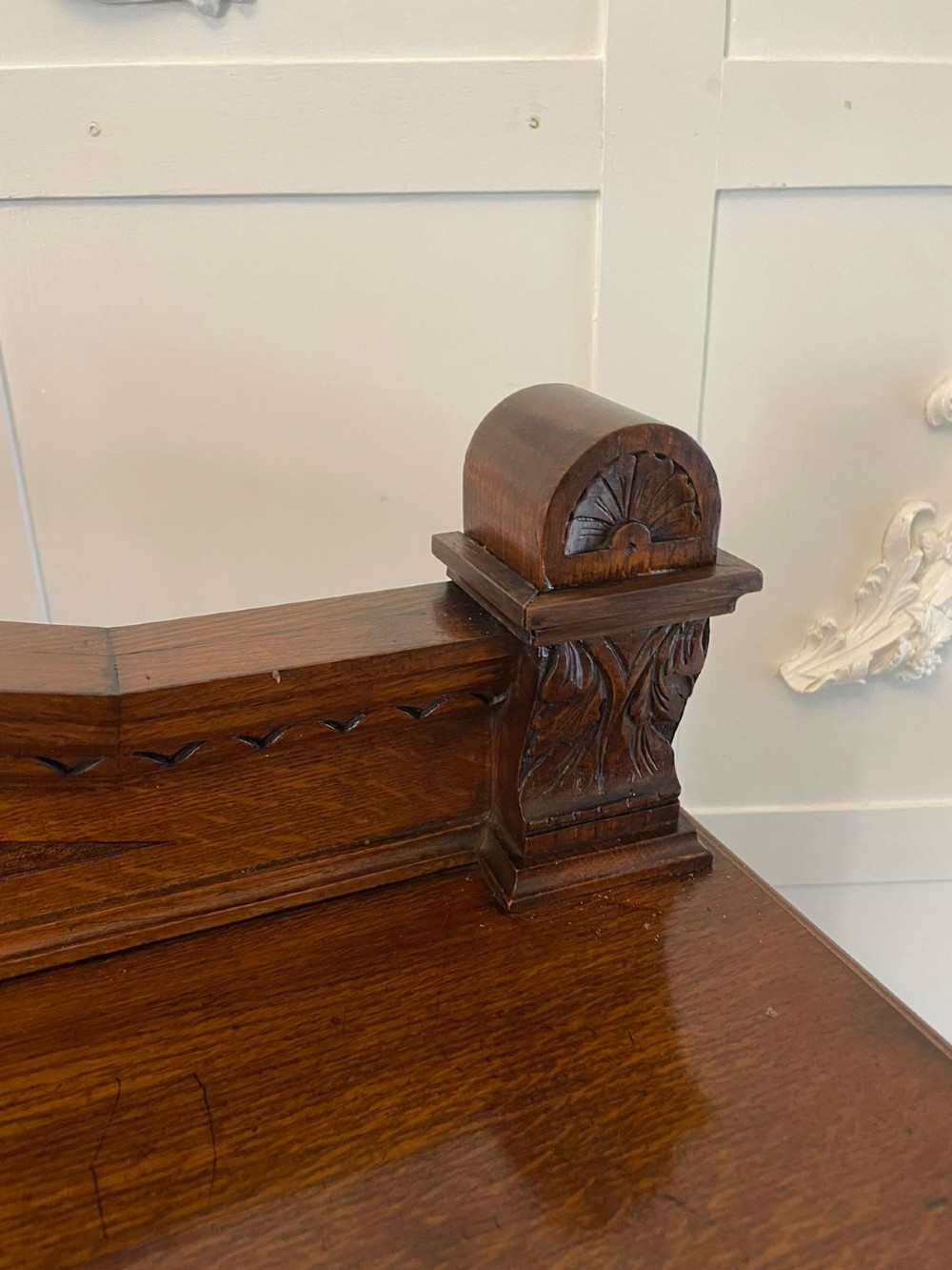 A three-tiered dark oak antique dumbwaiter featuring carved column supports, a carved gallery cresting, and bun feet. View V