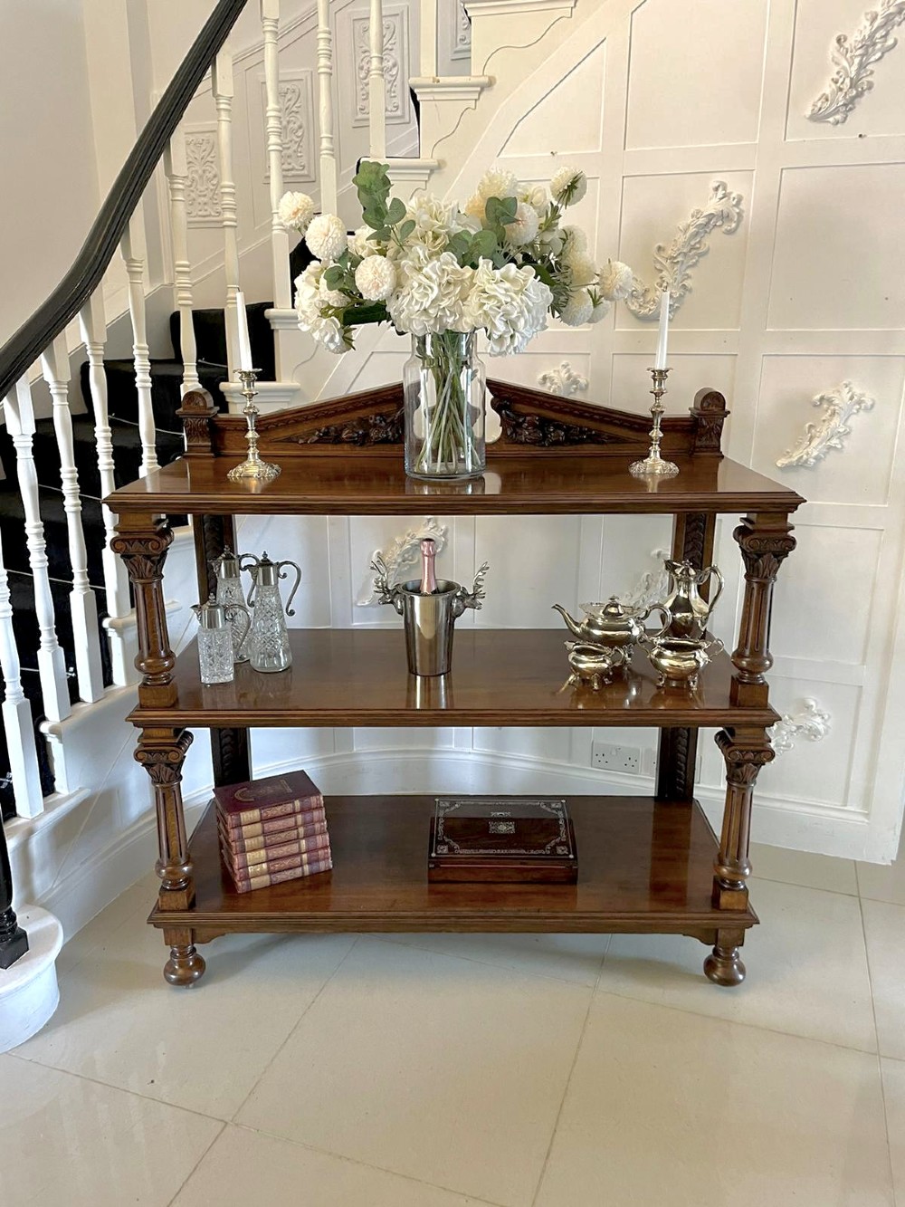 A three-tiered dark oak antique dumbwaiter featuring carved column supports, a carved gallery cresting, and bun feet. View VII