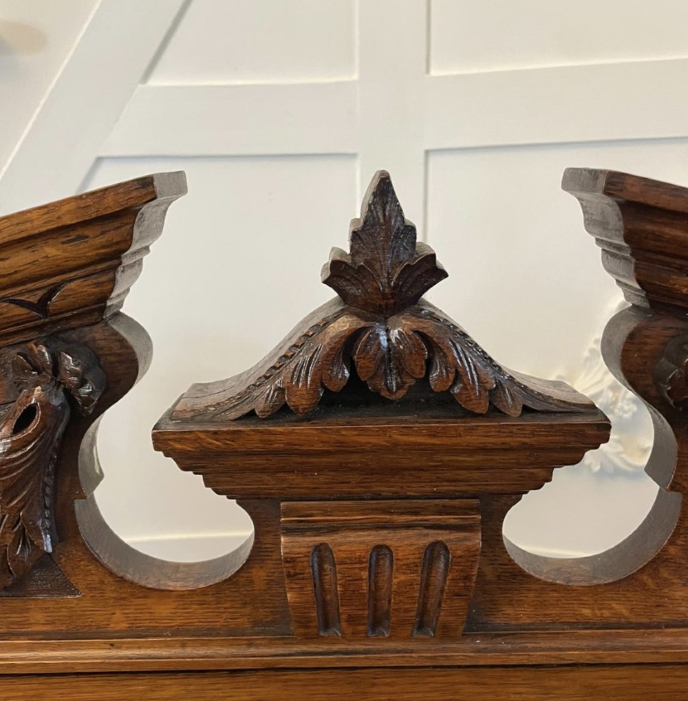 A three-tiered dark oak antique dumbwaiter featuring carved column supports, a carved gallery cresting, and bun feet. View VIII
