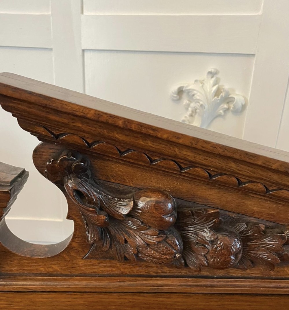 A three-tiered dark oak antique dumbwaiter featuring carved column supports, a carved gallery cresting, and bun feet. View XII