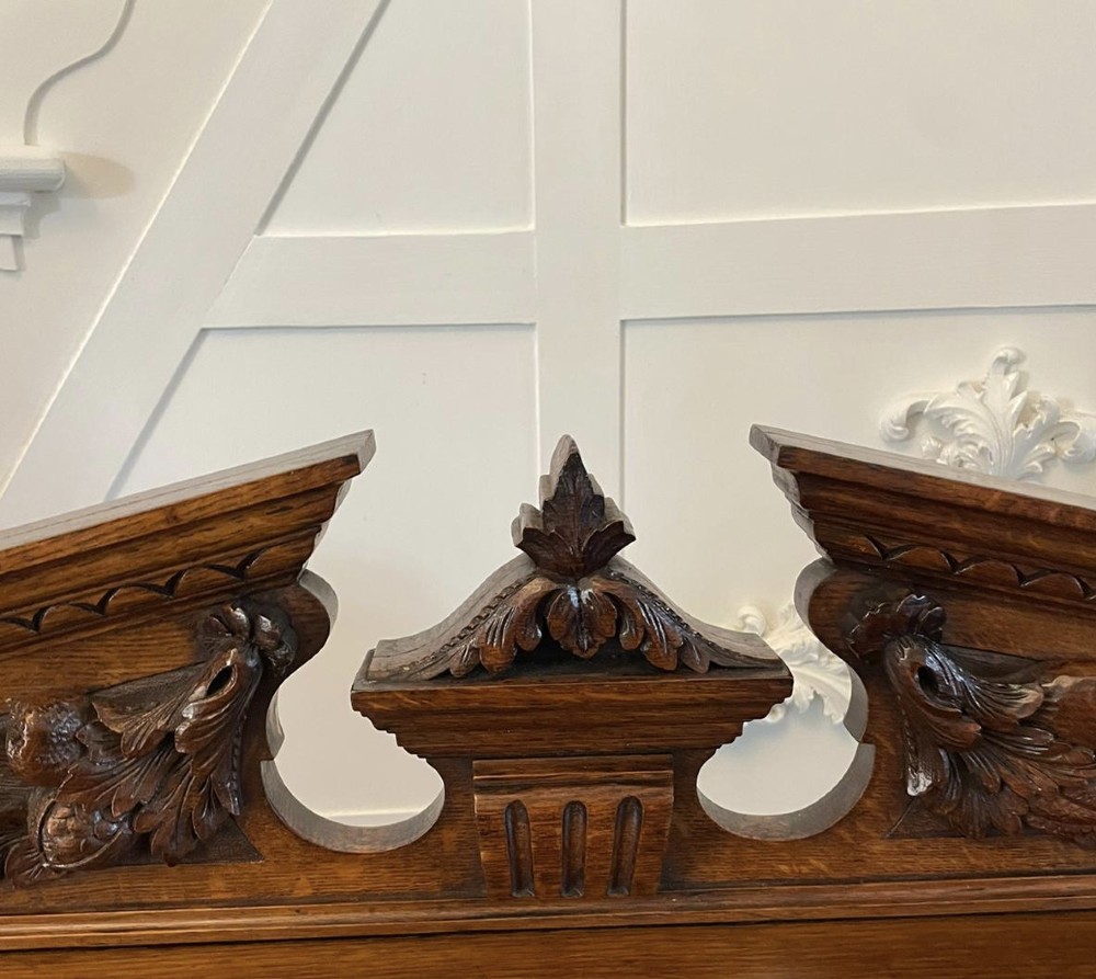 A three-tiered dark oak antique dumbwaiter featuring carved column supports, a carved gallery cresting, and bun feet. View XIV