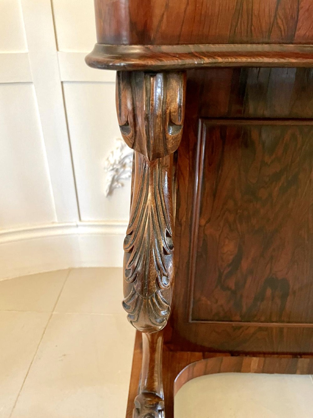 A Victorian rosewood Davenport desk featuring a sloped dark green leather writing surface, decorative brass gallery rail, carved cabriole front supports, and side drawers. View VII