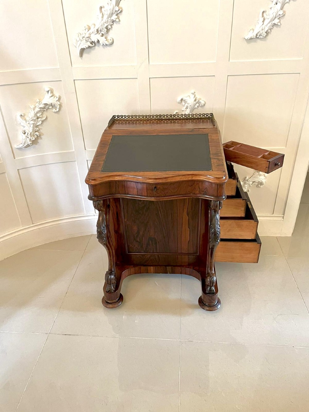 A Victorian rosewood Davenport desk featuring a sloped dark green leather writing surface, decorative brass gallery rail, carved cabriole front supports, and side drawers. View XI