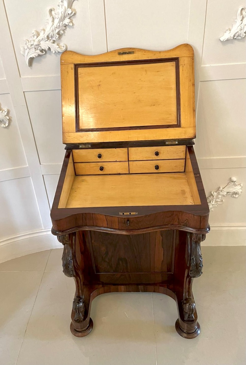 A Victorian rosewood Davenport desk featuring a sloped dark green leather writing surface, decorative brass gallery rail, carved cabriole front supports, and side drawers. View XIII