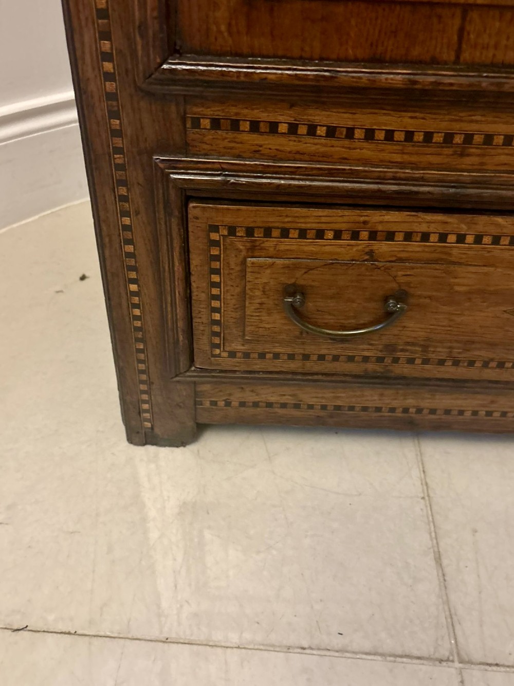A seventeenth-century oak mule chest with three rectangular panelled sections containing central diamond floral marquetry inlays positioned above two base drawers. View V