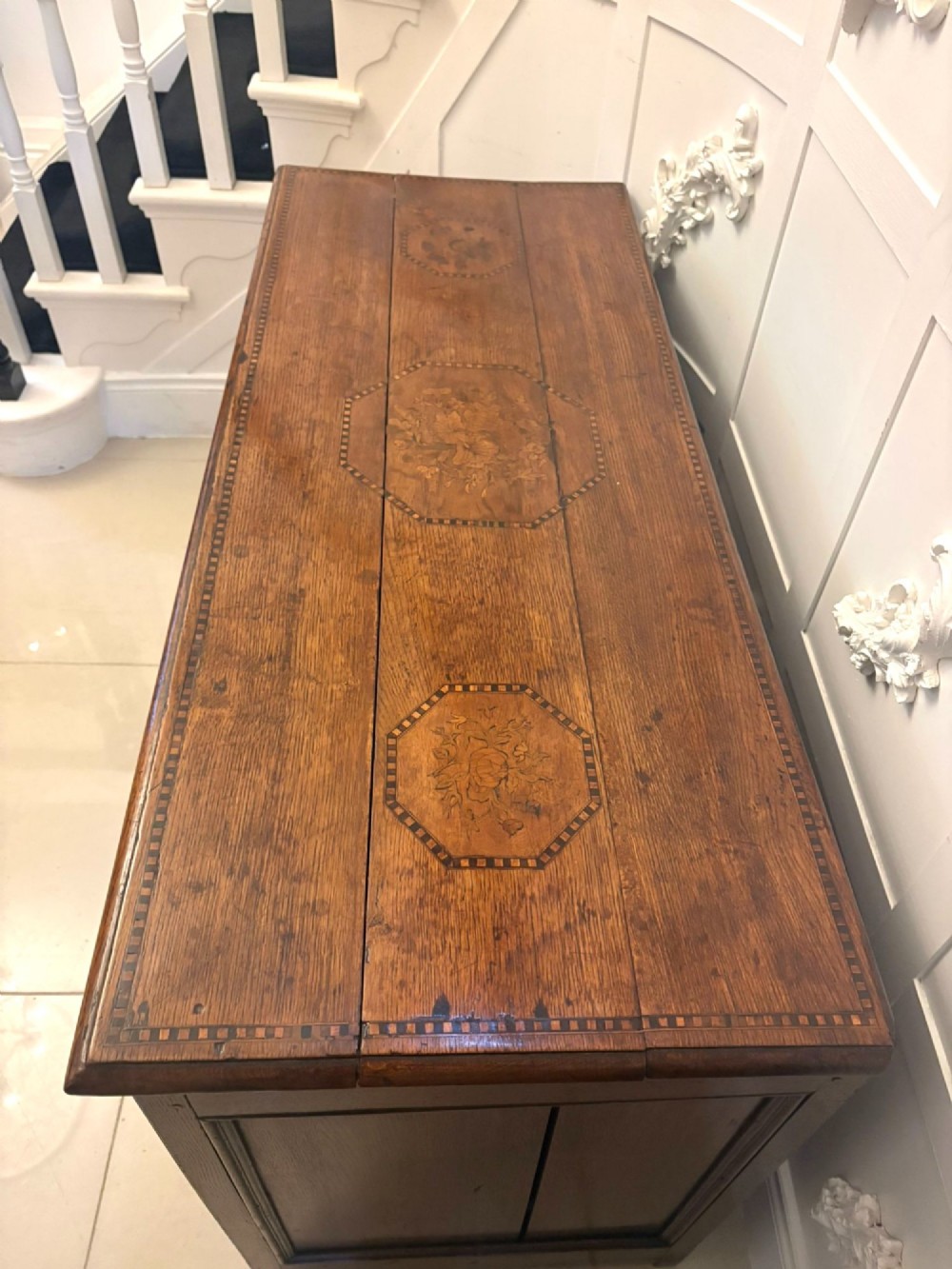 A seventeenth-century oak mule chest with three rectangular panelled sections containing central diamond floral marquetry inlays positioned above two base drawers. View IX