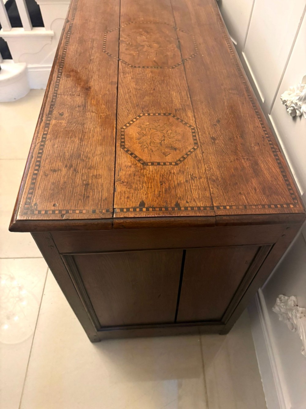 A seventeenth-century oak mule chest with three rectangular panelled sections containing central diamond floral marquetry inlays positioned above two base drawers. View X