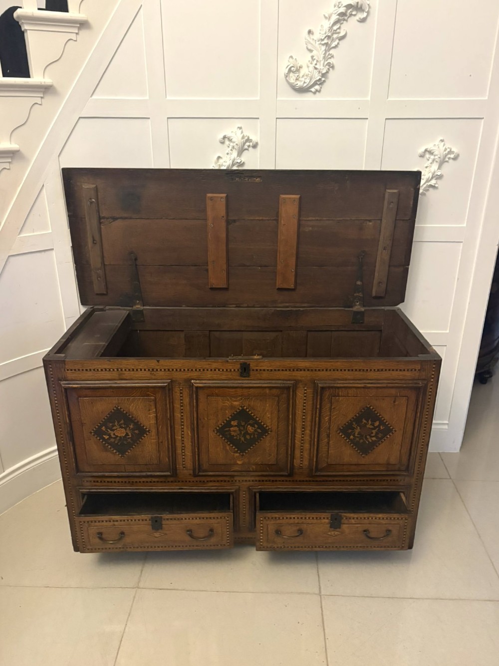 A seventeenth-century oak mule chest with three rectangular panelled sections containing central diamond floral marquetry inlays positioned above two base drawers. View XI