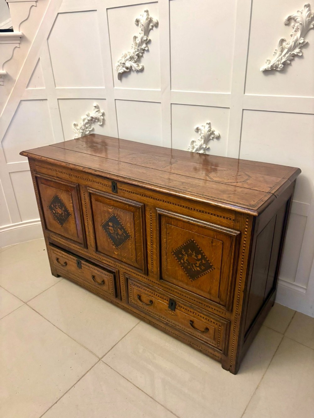 A seventeenth-century oak mule chest with three rectangular panelled sections containing central diamond floral marquetry inlays positioned above two base drawers. View XIII