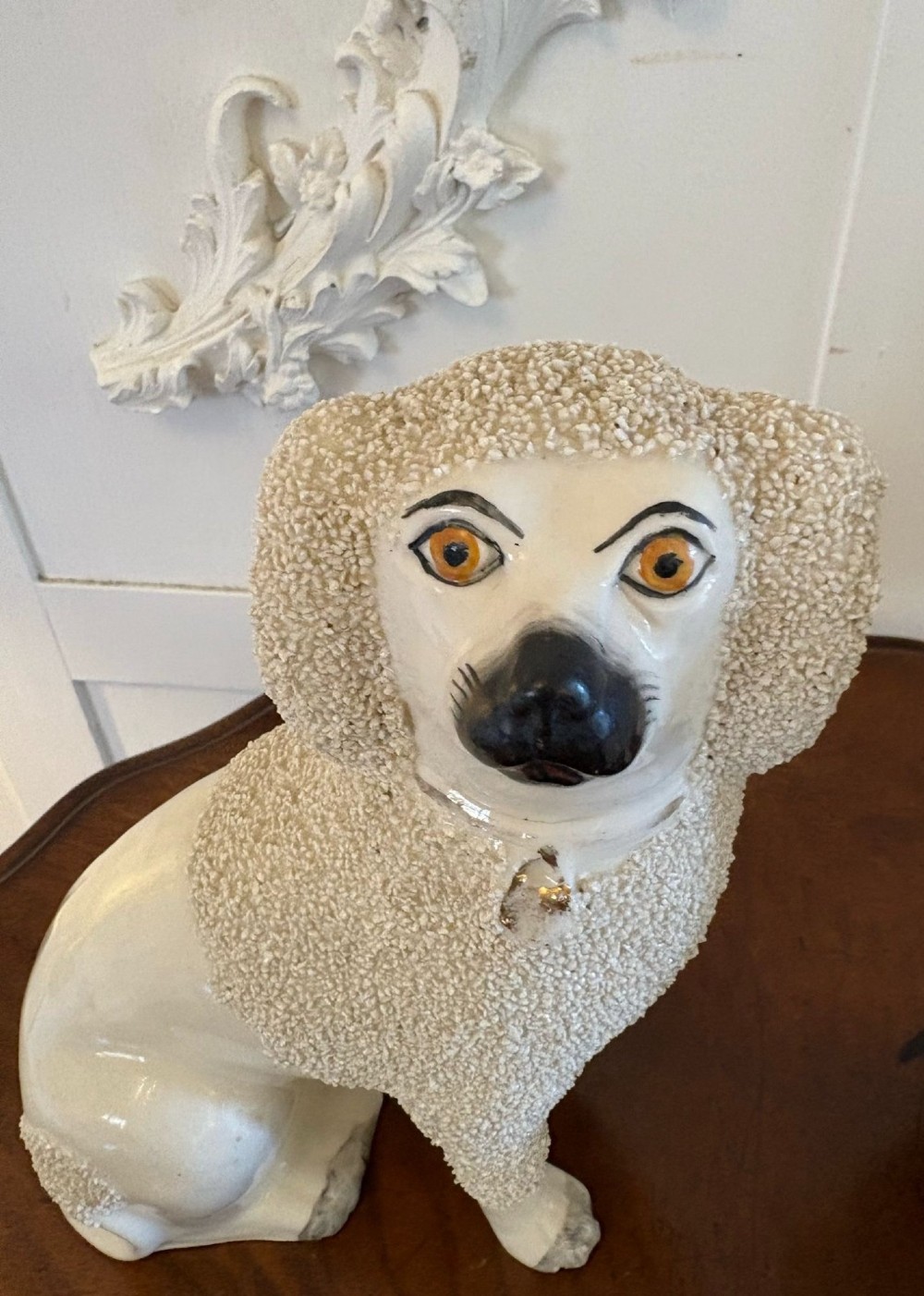 A matching pair of Victorian cream earthenware Staffordshire poodle figurines sitting upright with hand-applied textured fur and gilded collar details. View II