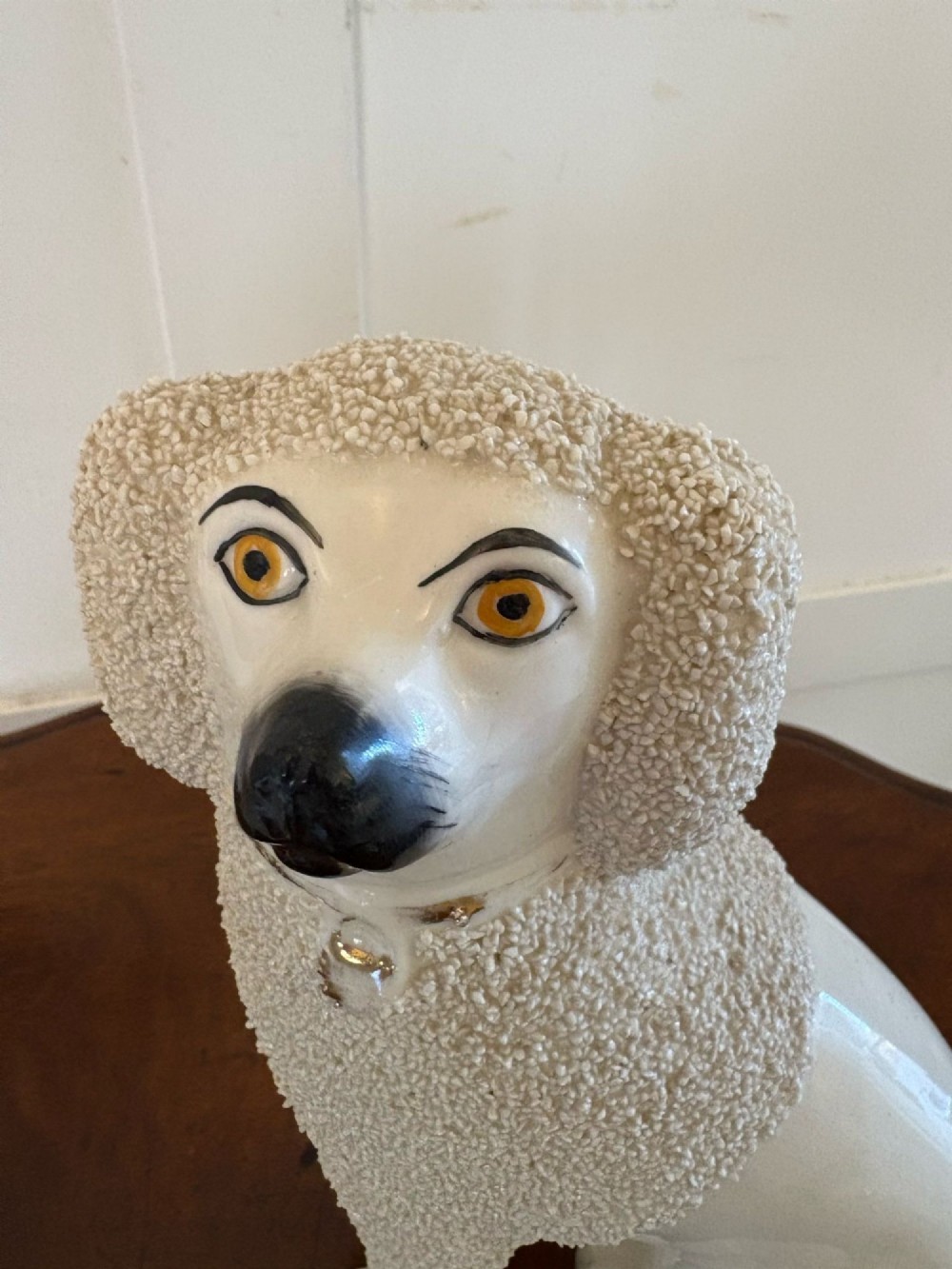 A matching pair of Victorian cream earthenware Staffordshire poodle figurines sitting upright with hand-applied textured fur and gilded collar details. View III